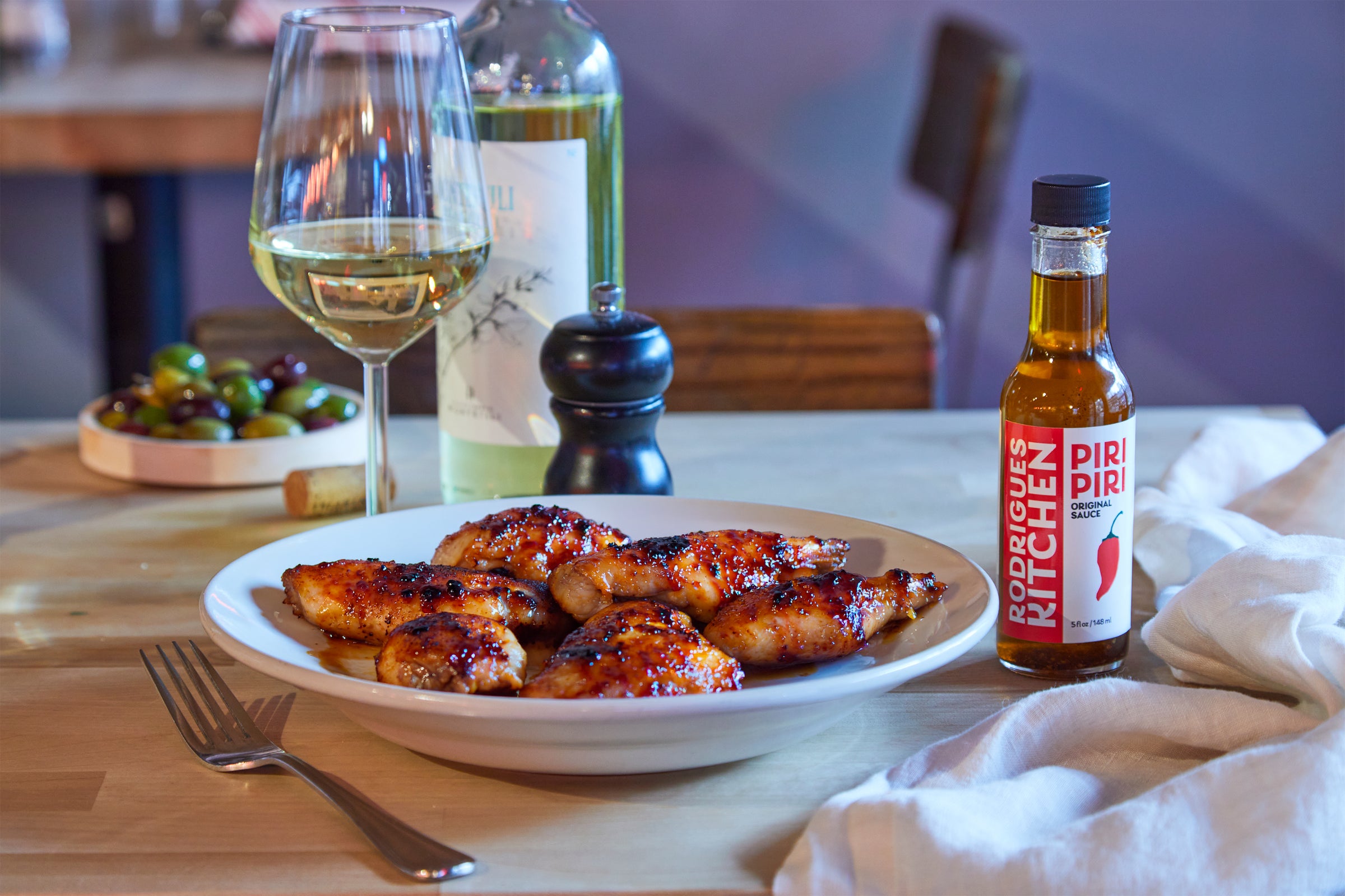 Rodrigues Kitchen Piri Piri sauce is being drizzled over grilled chicken in New York City.